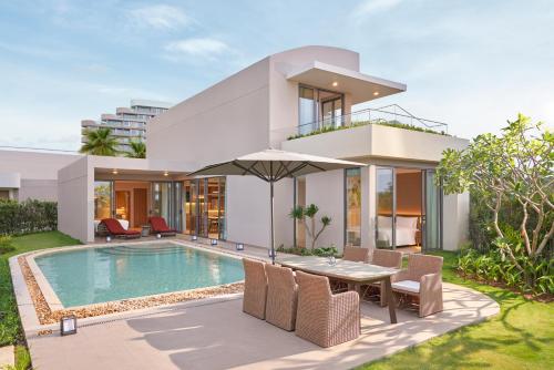 a house with a swimming pool and a table with an umbrella at IXORA Ho Tram By Fusion in Ho Tram