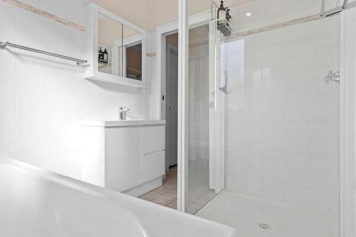 baño blanco con ducha y lavamanos en Fish Cottage Ulladulla - Linen not supplied - 3 bedroom house - sleeps 8 - pet friendly, en Ulladulla