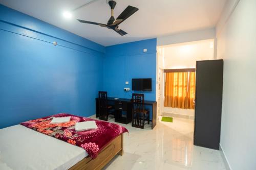 ein blaues Schlafzimmer mit einem Bett und einem Schreibtisch in der Unterkunft Jungle Eco Mansion in Kāziranga