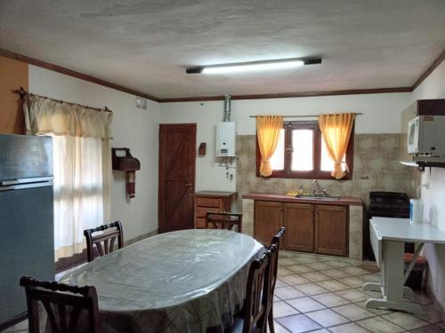 eine Küche mit einem Tisch und eine Küche mit einem Tisch und Stühlen in der Unterkunft Cabaña Los Lirios in Huerta Grande