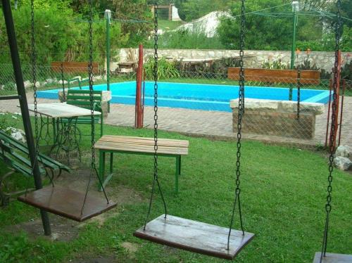 a swing set in a yard with a pool at Cabaña Los Lirios in Huerta Grande