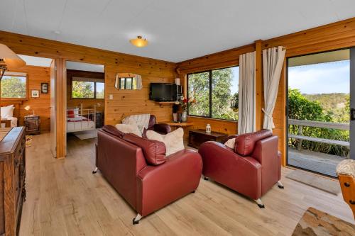 a living room with two chairs and a television at Enchanted Retreat - Kerikeri Holiday Home in Kerikeri