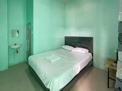 um quarto com uma grande cama branca e um lavatório em Antony Homestay near Pantai Pasir Putih Parbaba Mitra RedDoorz em Pangururan