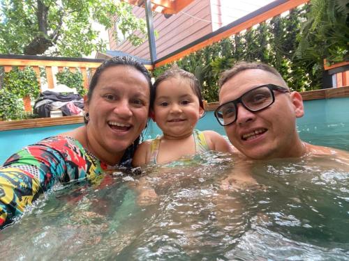 een man en een vrouw en een kind in een zwembad bij HOSTAL AONKEN in Coihaique