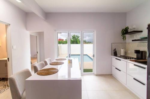 a white kitchen with a table and some chairs at Casa Marilina Aguadilla w/ Pool in Aguadilla