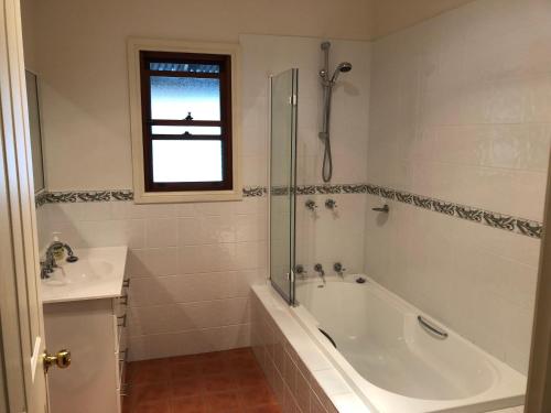 a white bathroom with a tub and a sink at Meriba B and B in Bundanoon