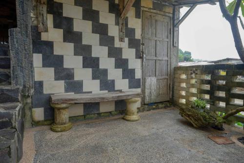 a bench on the side of a building with a checkered wall at Hotel Kampoeng Drini RedPartner in Brono