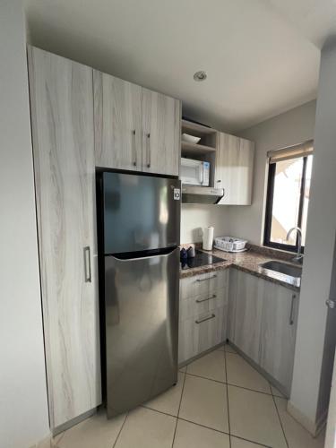 a kitchen with a stainless steel refrigerator and wooden cabinets at Sunny Tropical Condo And Rooftop Terrace in Coco