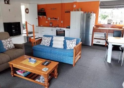 a living room with a blue couch and a table at Corotime ~ Boat Parking ~ Pet Friendly in Coromandel Town