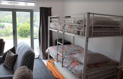 two bunk beds in a room with a window at Corotime ~ Boat Parking ~ Pet Friendly in Coromandel Town