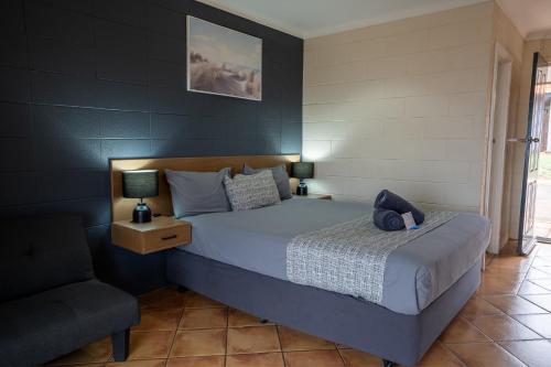 a bedroom with a bed and a chair at Hospitality Port Hedland in Port Hedland