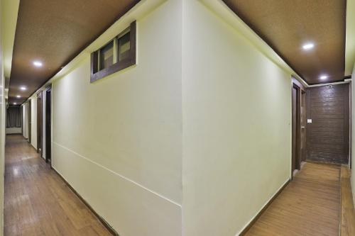 un pasillo de una casa con paredes blancas y suelo de madera en OYO Hotel Sree Balaji Residency, en Bodakdev