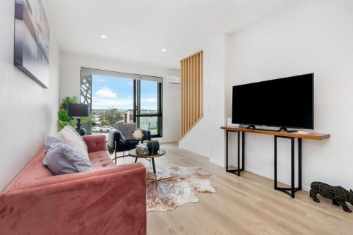 a living room with a red couch and a flat screen tv at Your home away from home located near Auckland CBD in Auckland