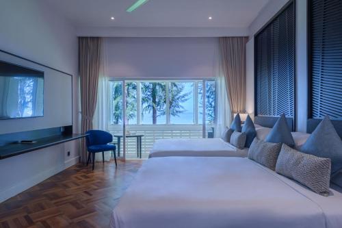 a hotel room with two beds and a television at Lone Pine, Penang, a Tribute Portfolio Resort in Batu Ferringhi