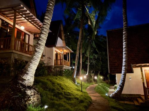 une maison avec des palmiers et une passerelle la nuit dans l'établissement Green Coco Suite, à Nusa Penida