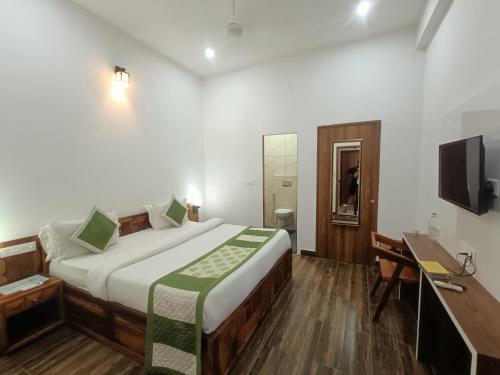 um quarto com uma cama, uma secretária e uma televisão em Hotel Dream Orchid em Pushkar
