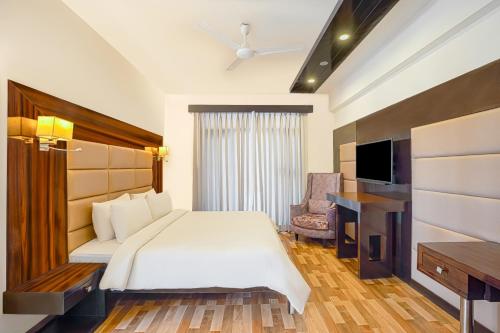 ein Hotelzimmer mit einem Bett und einem TV in der Unterkunft Country Inn Tarika Goa Varca Beach in Varca