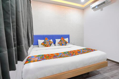 een slaapkamer met een groot bed met kleurrijke kussens bij FabHotel Vrundavan, Athwa in Bhatha
