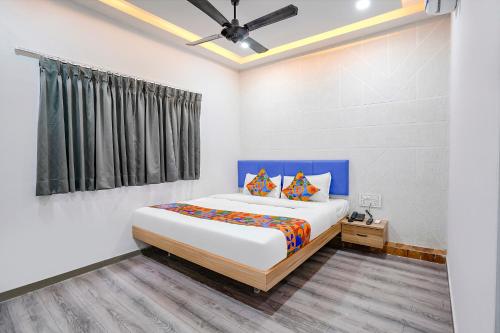 een slaapkamer met een groot bed met een blauw hoofdeinde bij FabHotel Vrundavan, Athwa in Bhatha