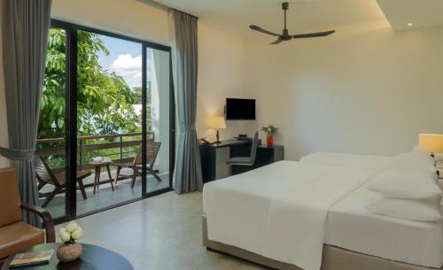 a bedroom with a white bed and a balcony at Eightfold Urban Resort in Siem Reap