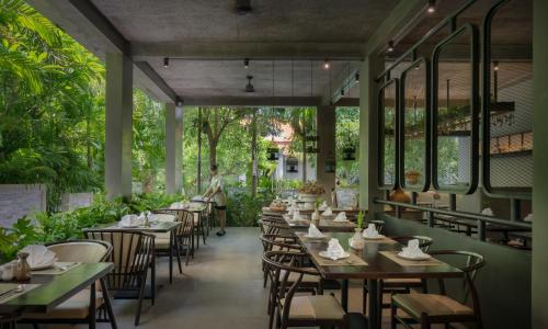 a dining room with tables and chairs and trees at Eightfold Urban Resort in Siem Reap