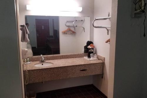 ein Badezimmer mit einem Waschbecken und einem großen Spiegel in der Unterkunft OSU 2 Queen Beds Hotel Room 133 Hot Tub Booking in Stillwater