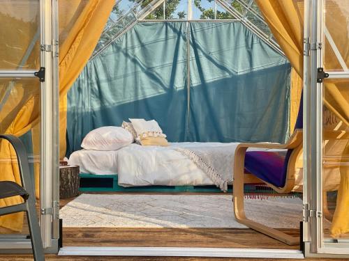 - un lit dans une tente avec une chaise dans l'établissement Langaland Glamping, à Susenii Bîrgăului
