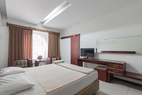 a bedroom with a bed and a desk and a television at Istana Hotel Bandung Mitra RedDoorz in Bandung