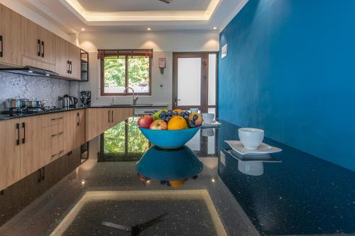 a blue kitchen with a bowl of fruit on a table at Maison D'Aaryan in Anse aux Pins