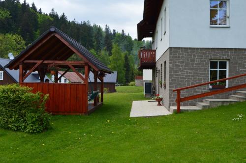 a building with a gazebo next to a house at Penzion U pily in Paseky nad Jizerou