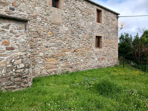 an old stone building with grass in front of it at Piedad Fernández Fernández Gestión de Inmuebles IV in Burela de Cabo