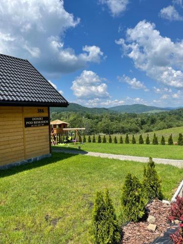 a yard with a building and a view of a field at Domki Pod Beskidem in Wysowa-Zdrój