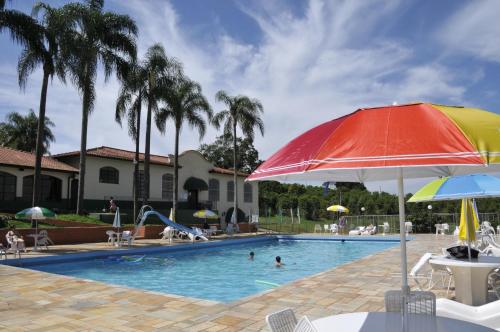 a pool with an umbrella and people in the water at Hotel Fazenda São Matheus in Serra Negra
