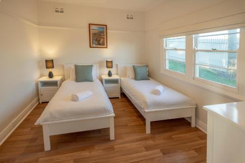 two beds in a room with two windows at Baileys Cottage in Adamstown