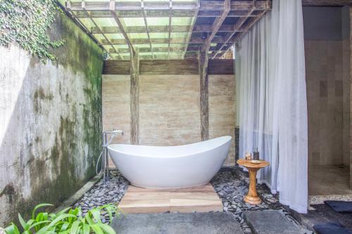 a bath tub sitting in the corner of a bathroom at KajaNe Mua at Ubud Bali in Ubud