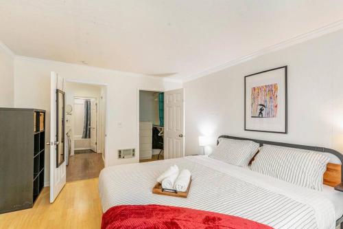 een witte slaapkamer met een groot bed met een rode deken bij Condo in Most sought after neighborhoods in Oakland