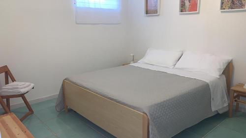 a bedroom with a white bed with a chair and a window at Il Giardino di Elettra in Palmadula