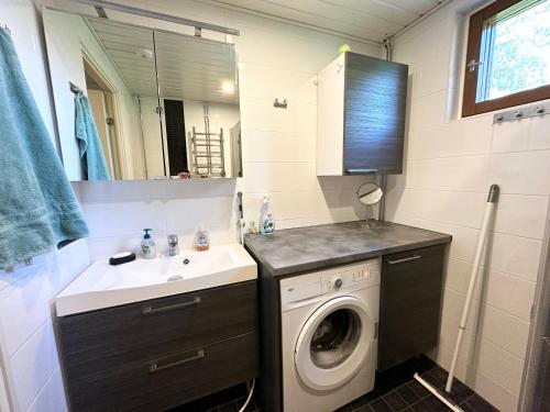 a bathroom with a washing machine and a sink at Spacious and modern apartment in Mikkeli