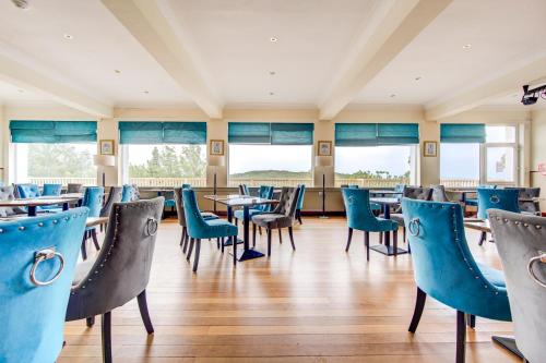 ein Restaurant mit blauen Stühlen, Tischen und Fenstern in der Unterkunft The Morar Hotel in Morar
