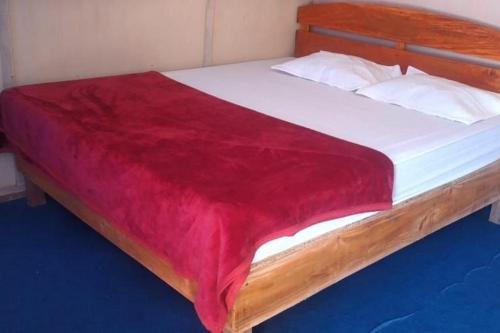 een bed met een rode deken erop bij Penginapan puncak Dua Mitra RedDoorz in Berastagi