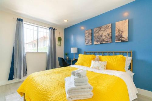 Un dormitorio azul con una cama amarilla con toallas. en Modern Cottage near many conveniences en Oakland