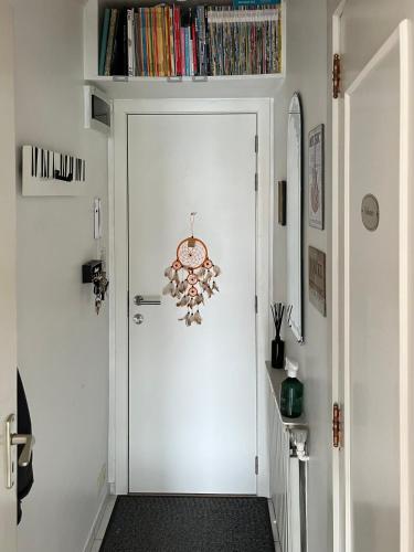 Un pasillo con una puerta blanca con un reloj. en Duinster Heist beach, en Knokke-Heist