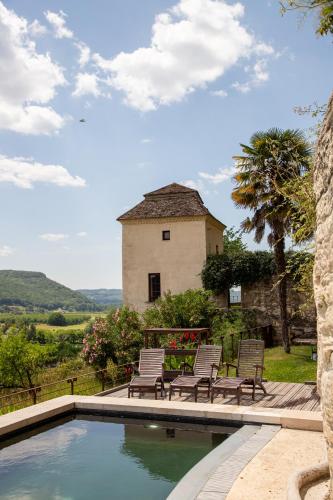 une piscine avec des chaises et un bâtiment en arrière-plan dans l'établissement Tour Pissarro, à Beynac-et-Cazenac
