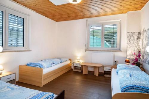 a bedroom with two beds and a table and two windows at 2 Zimmerwohnung in 88099 Neukirch ab 2 Übernachtungen in Neukirch