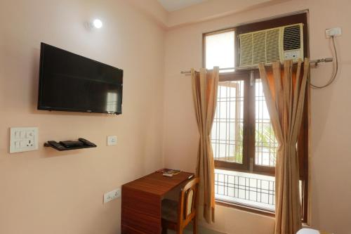 a room with a flat screen tv and a window at Hotel Surya Palace By Aura in Noida
