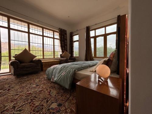 a bedroom with a bed with windows and a table at Nature Palace Farmstay in Shey