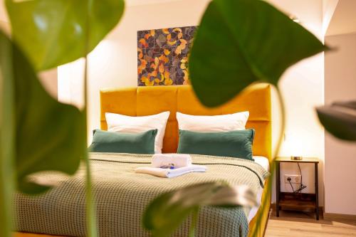 uma cama com cabeceira laranja e almofadas verdes em FeelgooD Apartments LOFT Zwickau CityCenter mit TG-Stellplatz, Netflix, Waipu-TV und Klima em Zwickau