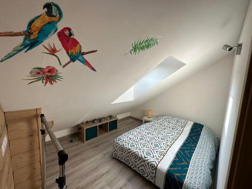 - une chambre avec un lit avec des oiseaux sur le mur dans l'établissement Appart chez Aurore et Jérôme La Bresse Centre Garage Wifi, à La Bresse
