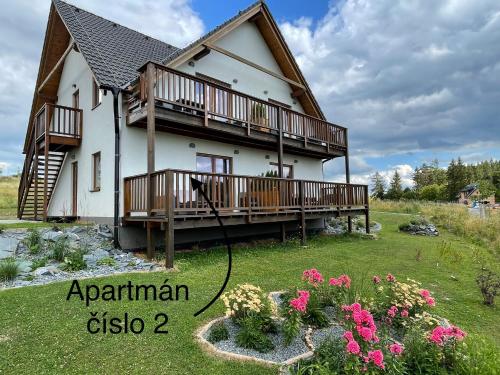 a house with a deck and a yard with flowers at Apartmány MAX in Vaclavov u Bruntalu