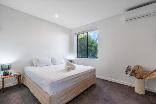 - une chambre blanche avec un lit et une fenêtre dans l'établissement Fayes Coastal Nest, à Kiama